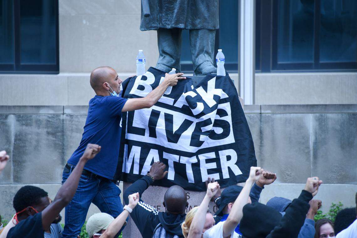 The Rev. Randy Fikki of Unity Southeast Kansas City, a church near Swope Park, places a water bottle on top of a Black Lives Matter banner to hold it in place.