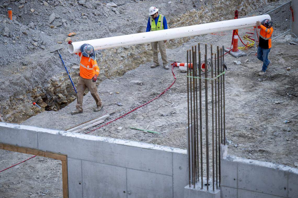 Construction workers in August carry pipe for a new stormwater drainage system at Barney Allis Plaza.