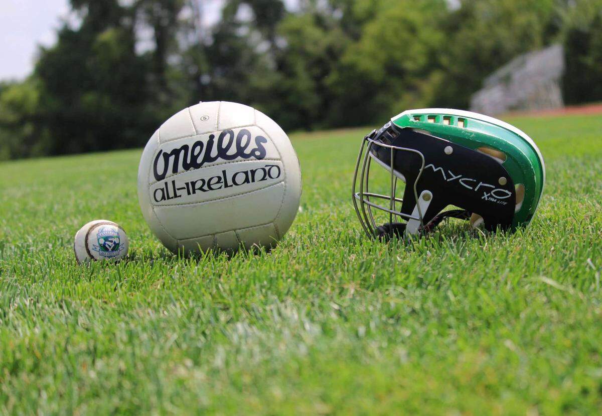 A Gaelic football and Irish hurling helmet sit in a field.