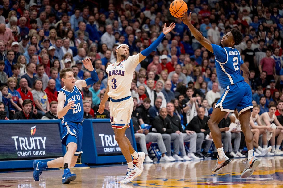 Kansas Jayhawks guard Dajuan Harris Jr. (3) and BYU Cougars guard Jaxson Robinson (2) reach for a loose ball during a college basketball game on Tuesday, Feb. 27, 2024, in Lawrence.