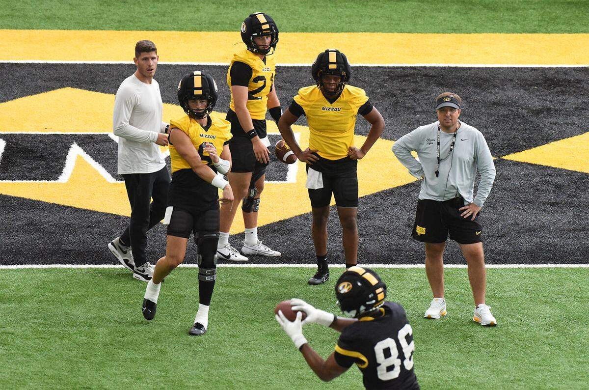 Mizzou quarterback Beau Pribula (9) throws a pass to tight end Jordon Harris (86) while quarterback Sam Horn (21), coach Eli Drinkwitz, right, and offensive coordinator Kirby Moore look on during the second practice of fall camp July 29, 2025, at the Stephens Indoor Facility.