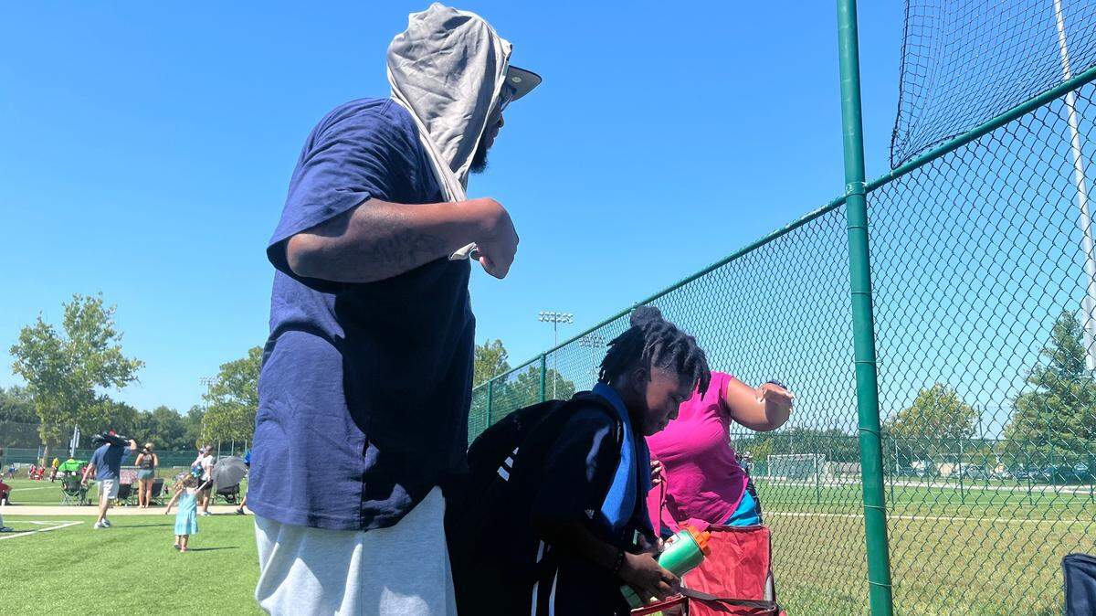 Orlando Strother and his son Noel cool off with cold towels and water after a soccer game at Compass Mineral Sporting Fields during a heat wave Sunday in Kansas City.