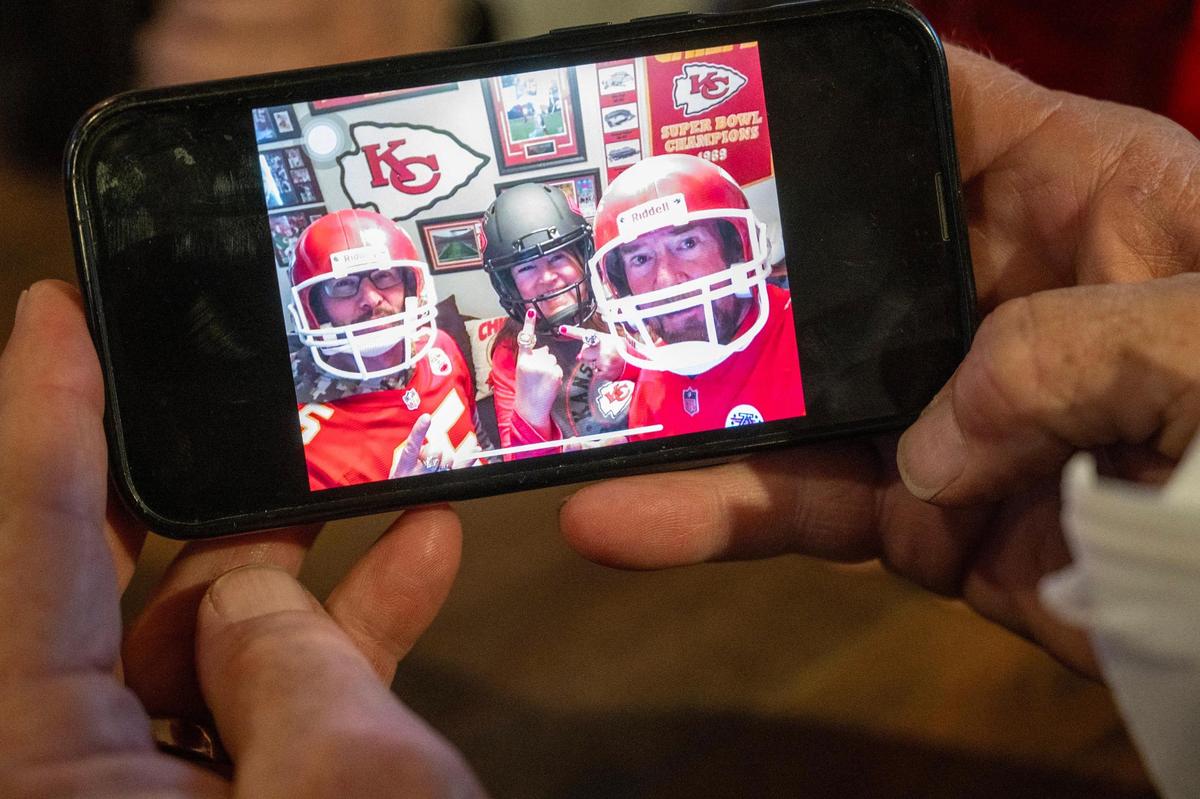 Dan Jernigan, a Kansas City Chiefs fan, shows a photo on his mobile device of himself, his wife Jane and his friend Joedy Gonzalez wearing their Chiefs helmets as part of a game day superstition.