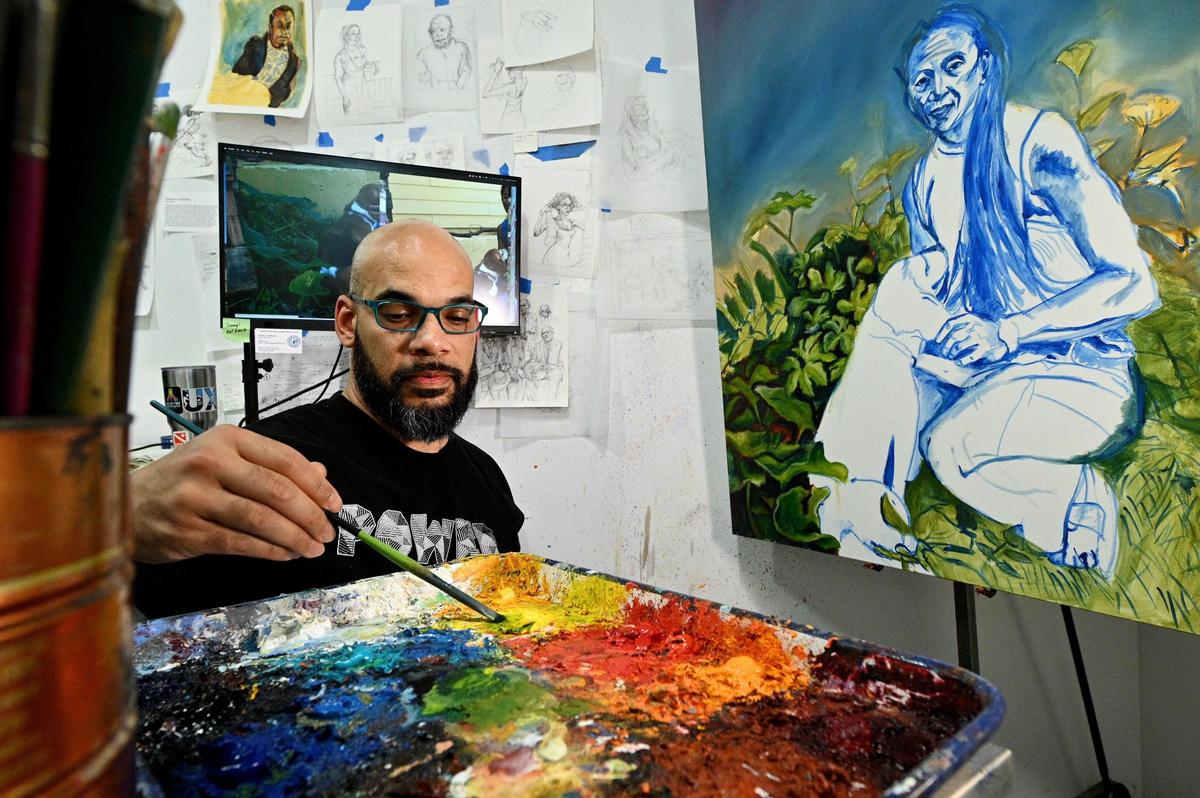 Kwanza Humphrey works on one of five portraits he is creating for the new terminal at Kansas City International Airport. In his Overland Park studio recently, Humphrey, who paints from photographs he’s taken, works on the garden area surrounding his friend Andrea.