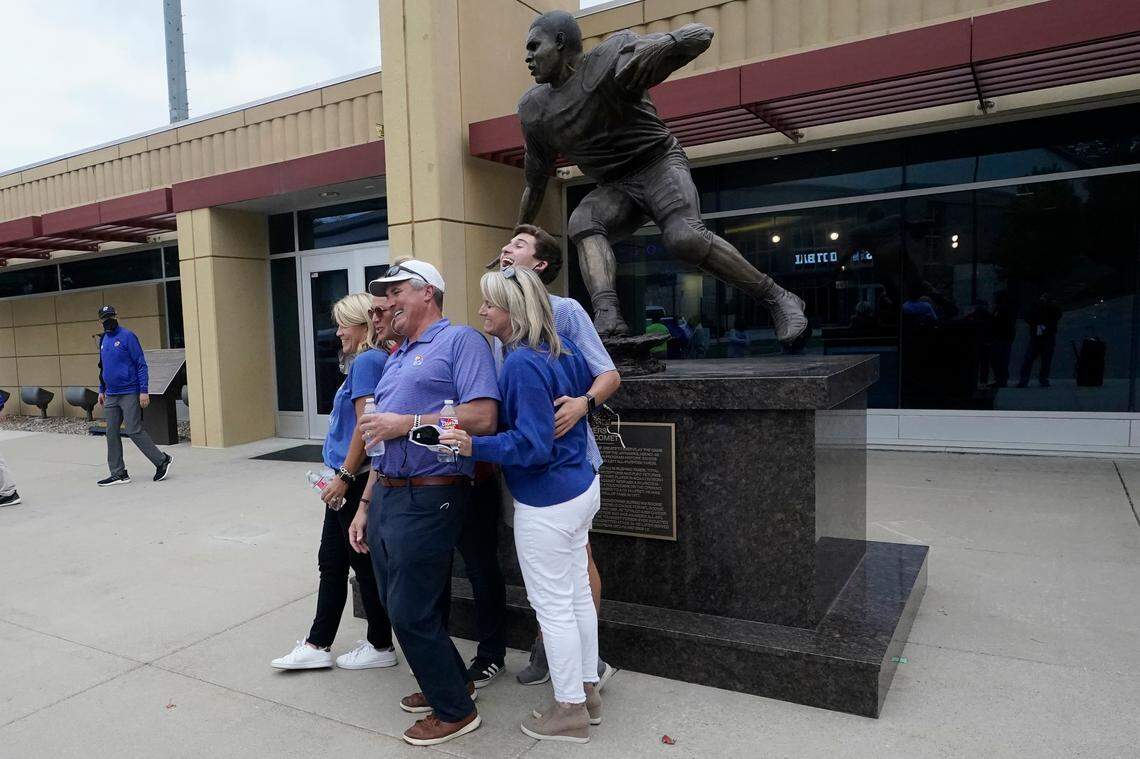 Fans pose for a photo next to a new statue of the late Jayhawks and NFL great Gale Sayers, which was dedicated in a ceremony during halftime of Saturday’s football game between Kansas and Oklahoma State at Booth Memorial Stadium in Lawrence, Kan.