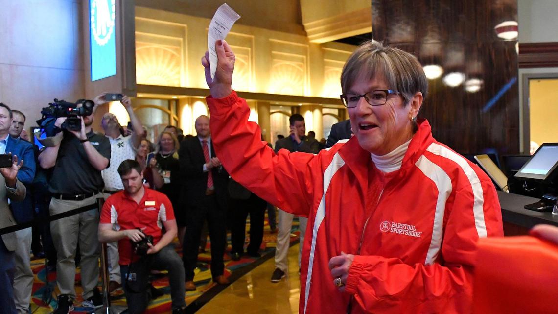 Kansas Gov. Laura Kelly places the first legal sports bet in Kansas in 2022 and turns toward an enthusiastic crowd after putting her money on the Kansas City Chiefs.