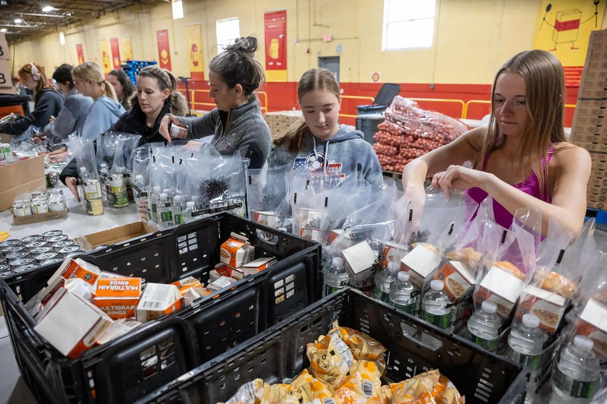 Volunteers Gretchen Schmanke of Overland Park, from left, Meagan Witkowski, of Overland Park, her daughter, Audrey Witkowski, 13, and Emme Walker, 14, of Kansas City packed BackSnacks at Harvesters on the MLK Day of Service on Monday, Jan. 20, 2025, in Kansas City. The BackSnacks program provides food for elementary and some middles school students to take home over the weekend.