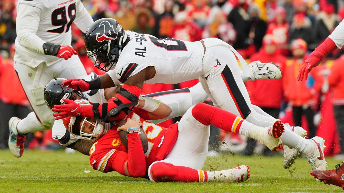 Kansas City Chiefs quarterback Patrick Mahomes (15) is sacked by Houston Texans linebacker Azeez Al-Shaair (top) and defensive tackle Tommy Togiai (72) during the first quarter of a 2025 AFC divisional round game at GEHA Field at Arrowhead Stadium.