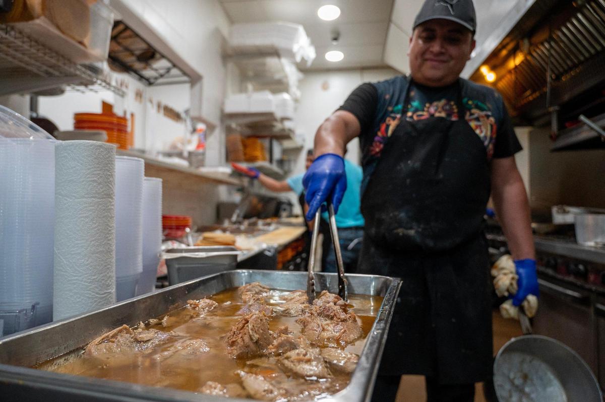 Ariel Rosas, head chef at Dos Reales Mexican restaurant, checks on carnitas that are cooked in a liquid that contains Mexican beer and Mexican Coca-Cola, among other ingredients.
