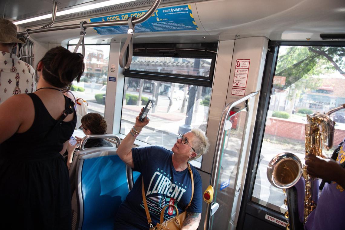 A woman holds up her phone to record video of Sass-A-Brass as the band plays on a Ride KC Streetcar prior to the City Market Pride month celebration.