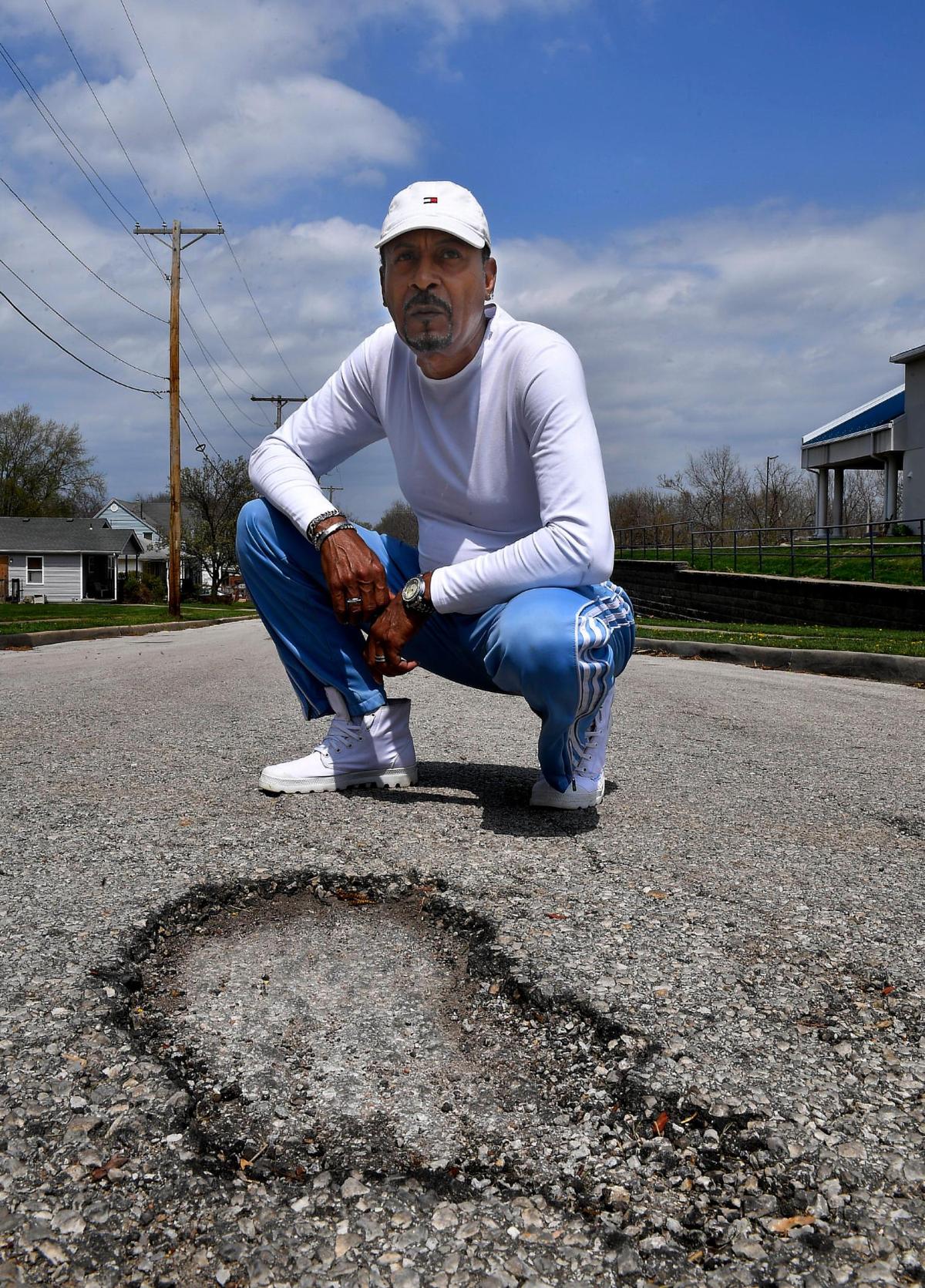 Dexter Murray, vice president of the Boston Heights and Mount Hope Neighborhood Association, is pictured with a pothole on Woodland Avenue near Linwood Boulevard. Murray said the patches that city crews lay down don’t work and in many cases make the problem worse.