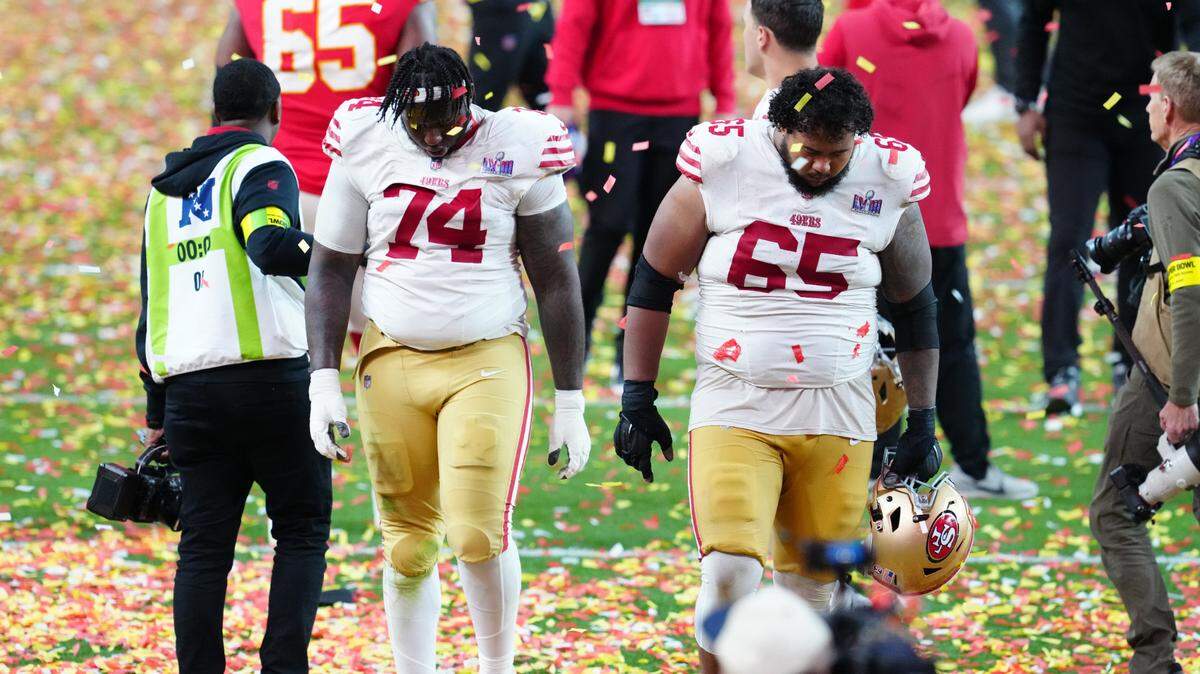 San Francisco 49ers offensive tackle Spencer Burford (74) and San Francisco 49ers guard Aaron Banks (65) leave the field after losing to the Kansas City Chiefs during overtime in Super Bowl LVIII at Allegiant Stadium.