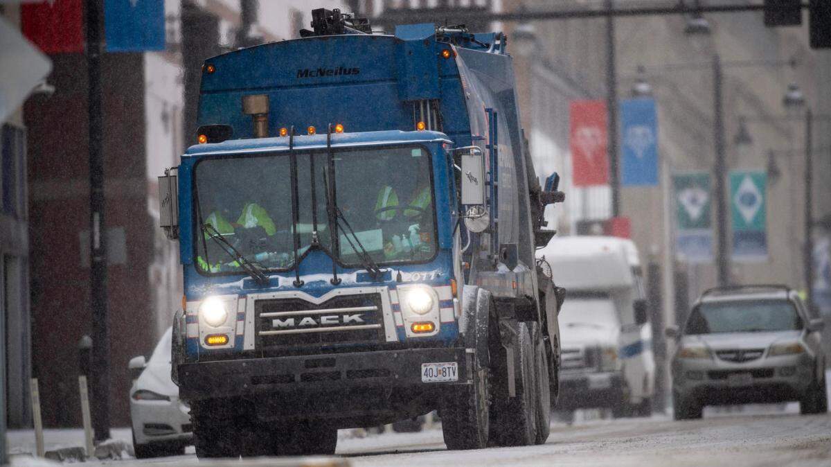 A Republic Services solid waste collection truck navigates along a snowy Grand Boulevard amid light snow and frigid temperatures on Monday, Jan. 15, 2024, in Kansas City.