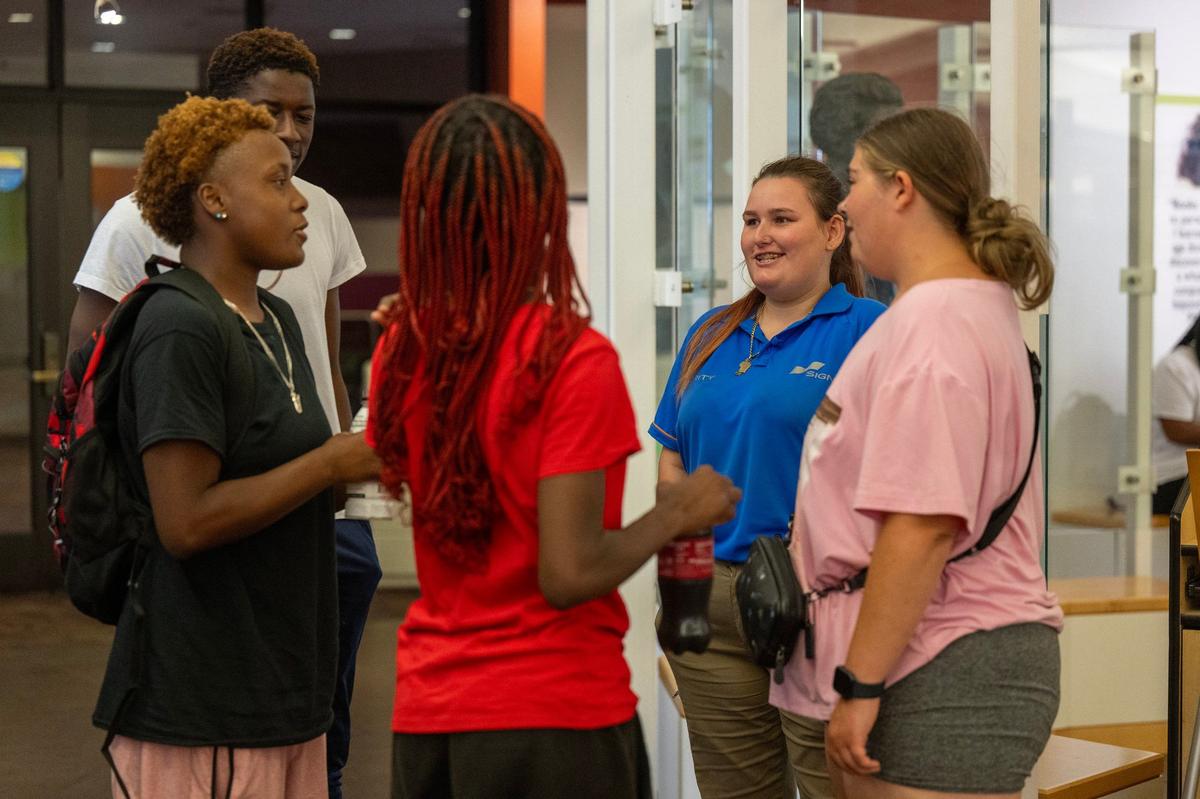 Wearing a blue shirt, Geneva Torrence, right, is easily identified as a security officer. She talks with a group of teens and young adults who greeted her by name at the Lucile H. Bluford branch of the Kansas City Public Library on Tuesday, Sept. 17, 2024, in Kansas City.