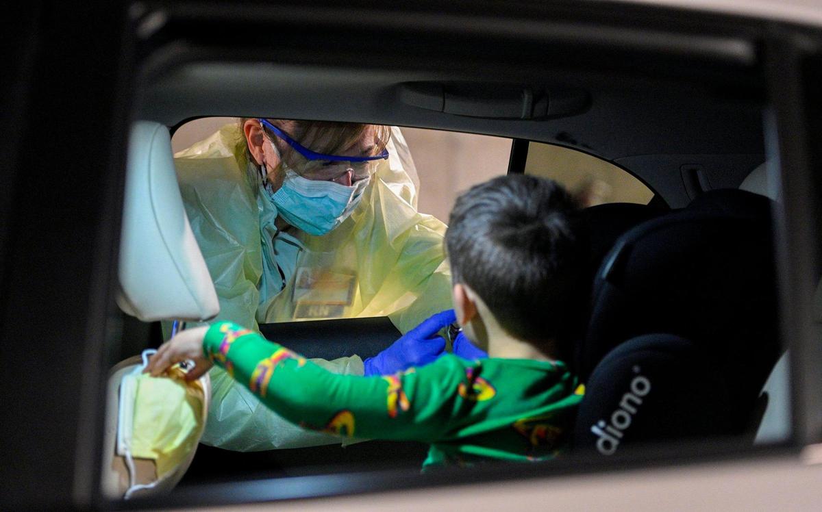 At the drive-thru COVID-19 testing site at University Health, registered nurse Jessica Evans collects a sample for testing from the mouth of 5-year-old Fletcher Moyes of Stilwell in Johnson County.