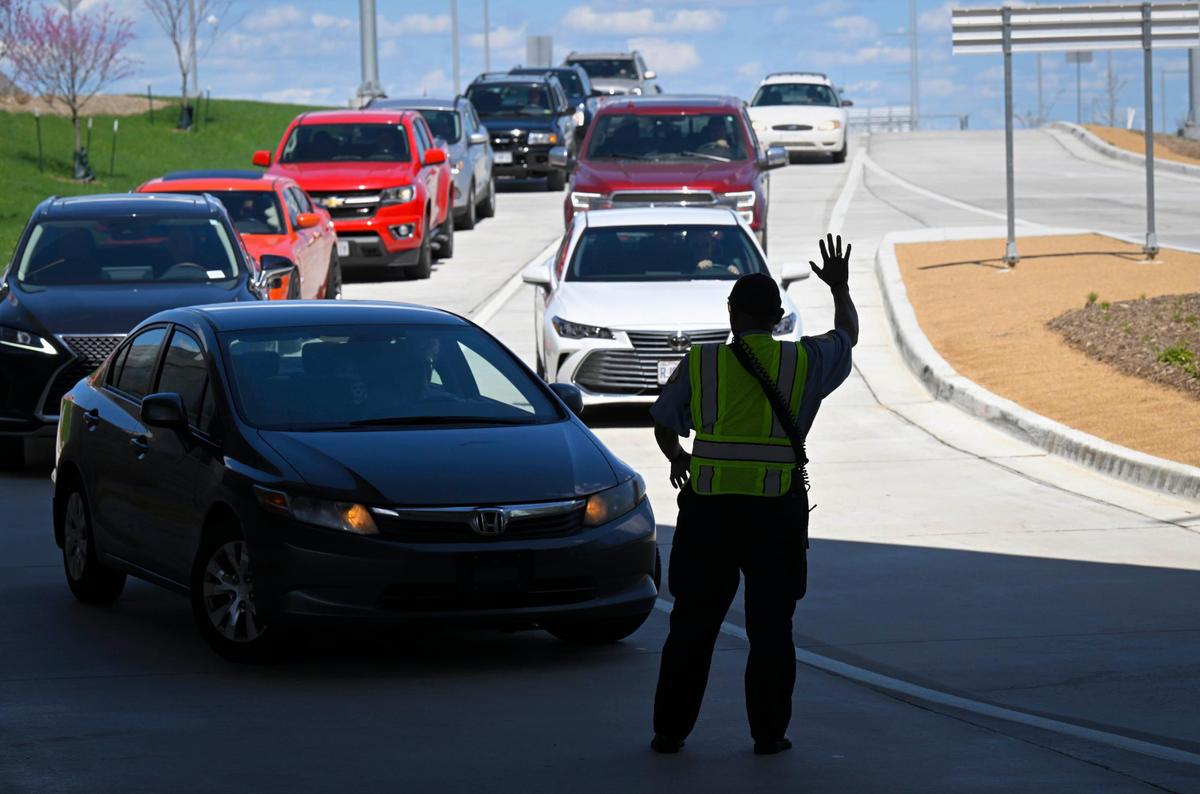 Clyde Kemp Jr., a traffic control officer, signals for drivers to slow down at Kansas City International Airport.