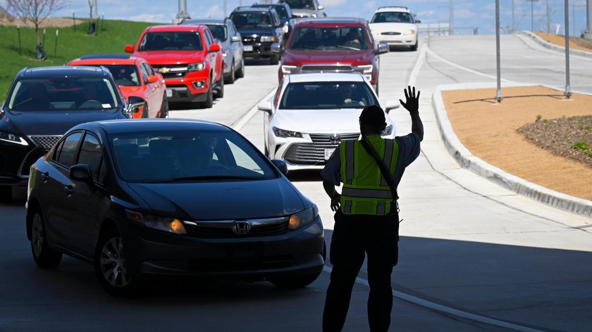 Clyde Kemp Jr., a traffic control officer, signals for drivers to slow up as they arrive Friday to pick up passengers at the new terminal at Kansas City International Airport. The airport is expecting an increase in passenger traffic with the upcoming NFL Draft.