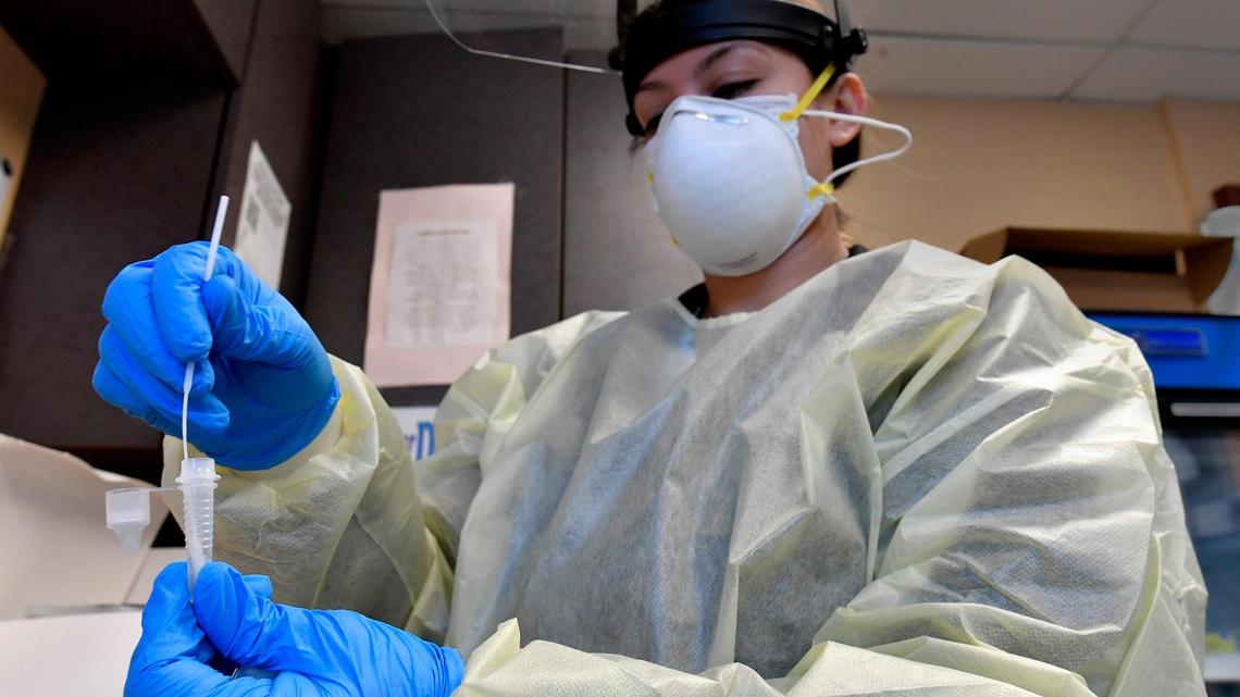 After taking nasal swab for a COVID-19 test from a patient in a drive-thru testing line, medical assistant Breana Slusser completes the test in a lab Tuesday afternoon at the Family Health Care Clinic in Kansas City, Kansas.
