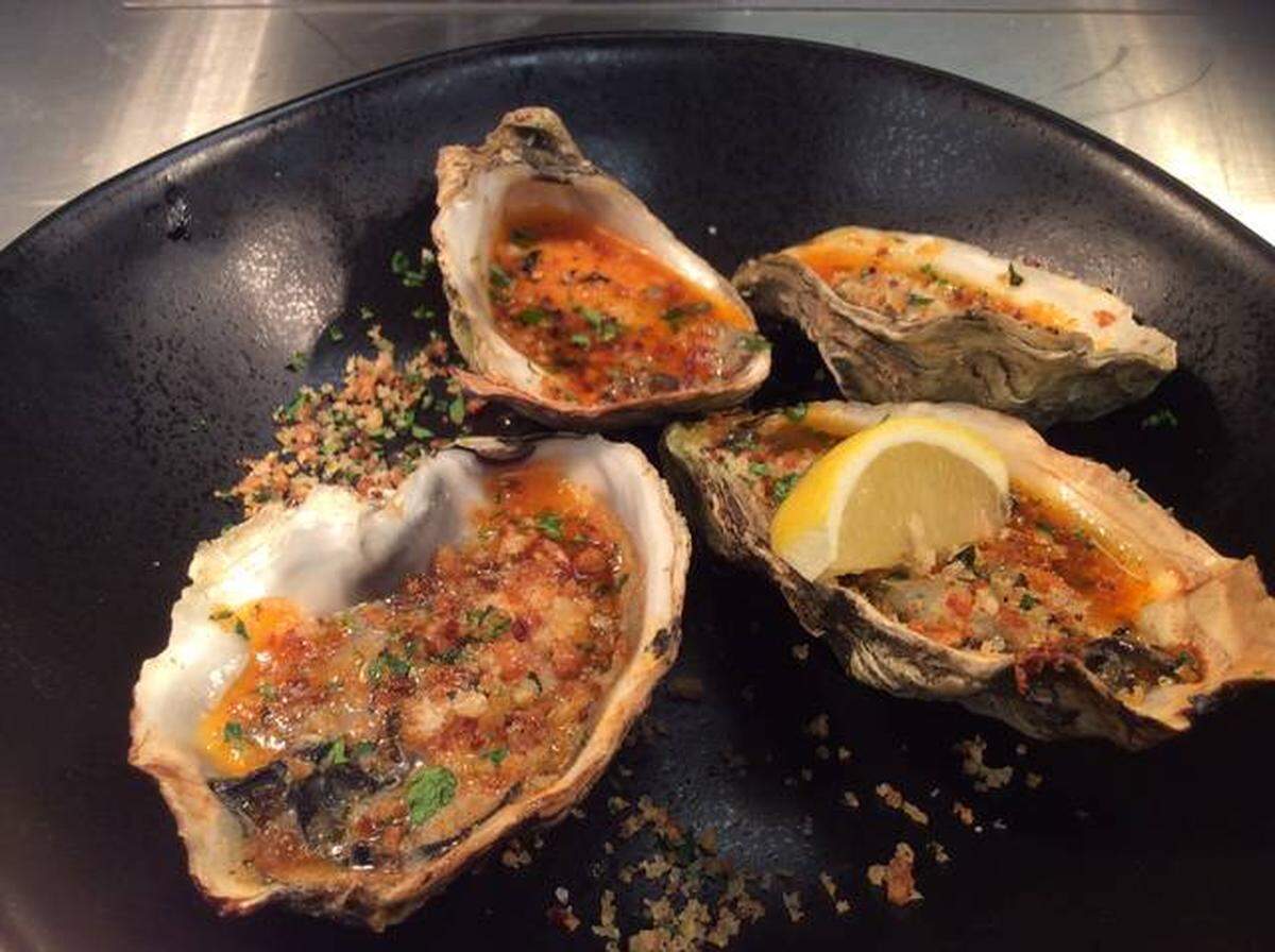 Farina’s broiled oysters with paprika butter, lemon, herbs and crumbs.