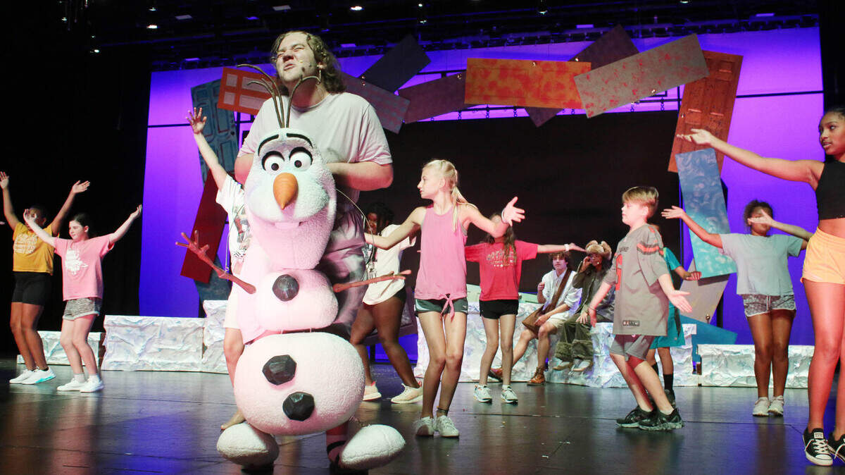 Backed by a group of younger Olathe students, Tyler Taylor rehearses a joyful scene as Olaf as part of the district-wide production of ‘Frozen’.