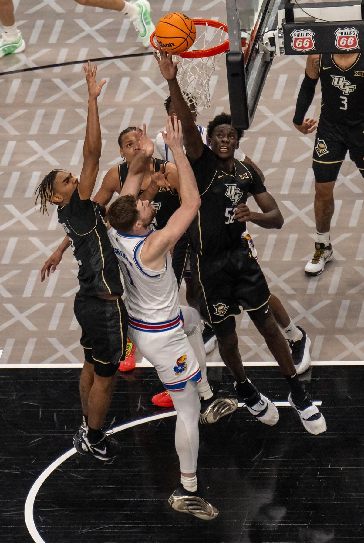 Kansas Jayhawks center Hunter Dickinson (1) shoots the ball while swarmed by UCF Knights players in the first half at the Big 12 Tournament at T-Mobile Center on Wednesday, March 12, 2025, in Kansas City.