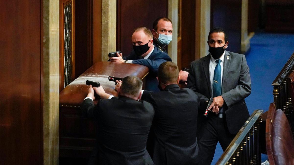 U.S. Capitol Police with guns drawn stand near a barricaded door as protesters try to break into the House Chamber at the U.S. Capitol on Wednesday, Jan. 6, 2021, in Washington. (AP Photo/Andrew Harnik)