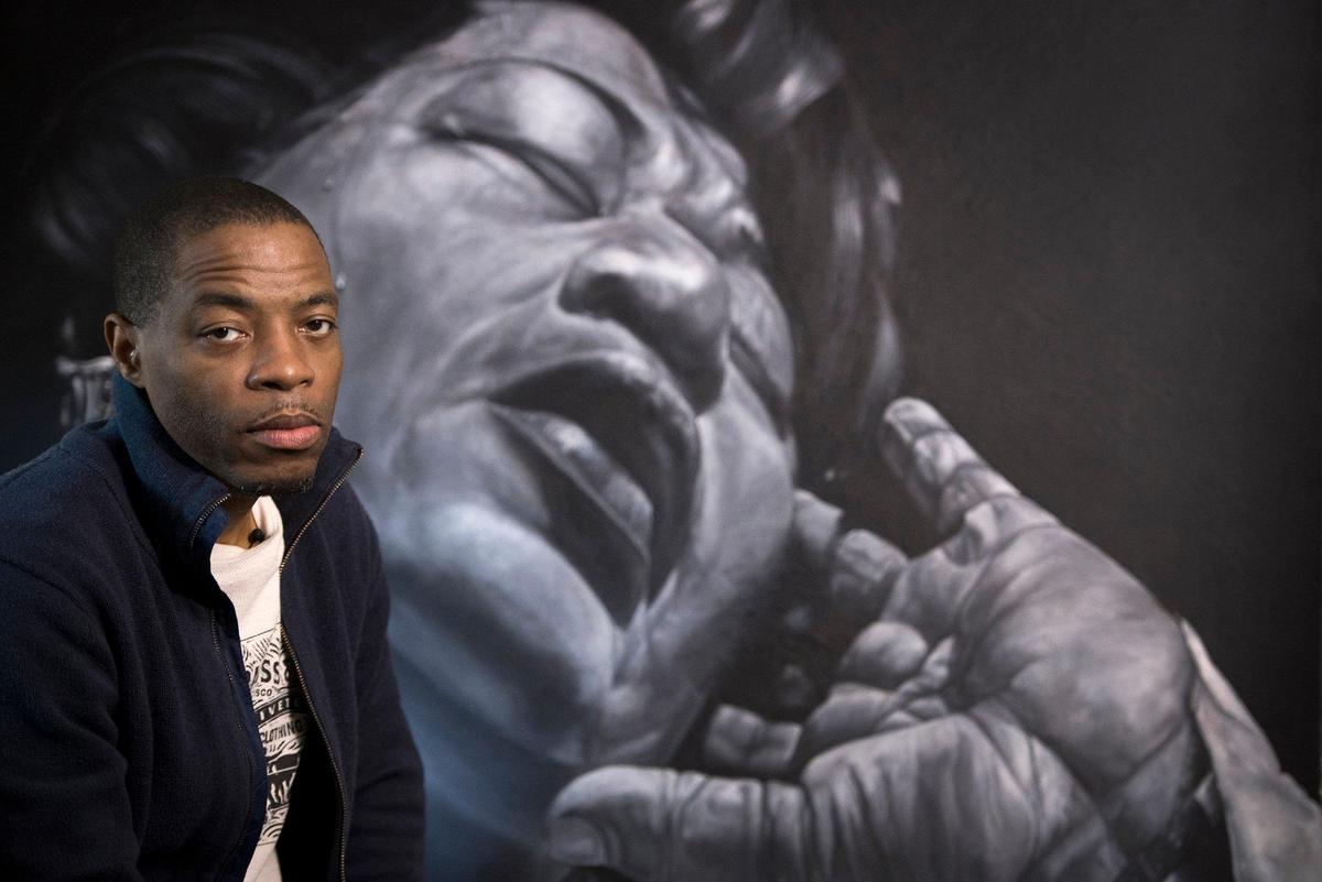 Artist Michael Brantley of Kansas City, Kansas, is a prolific painter, despite his illness. He sits in front of a portrait he painted of jazz great Ella Fitzgerald.