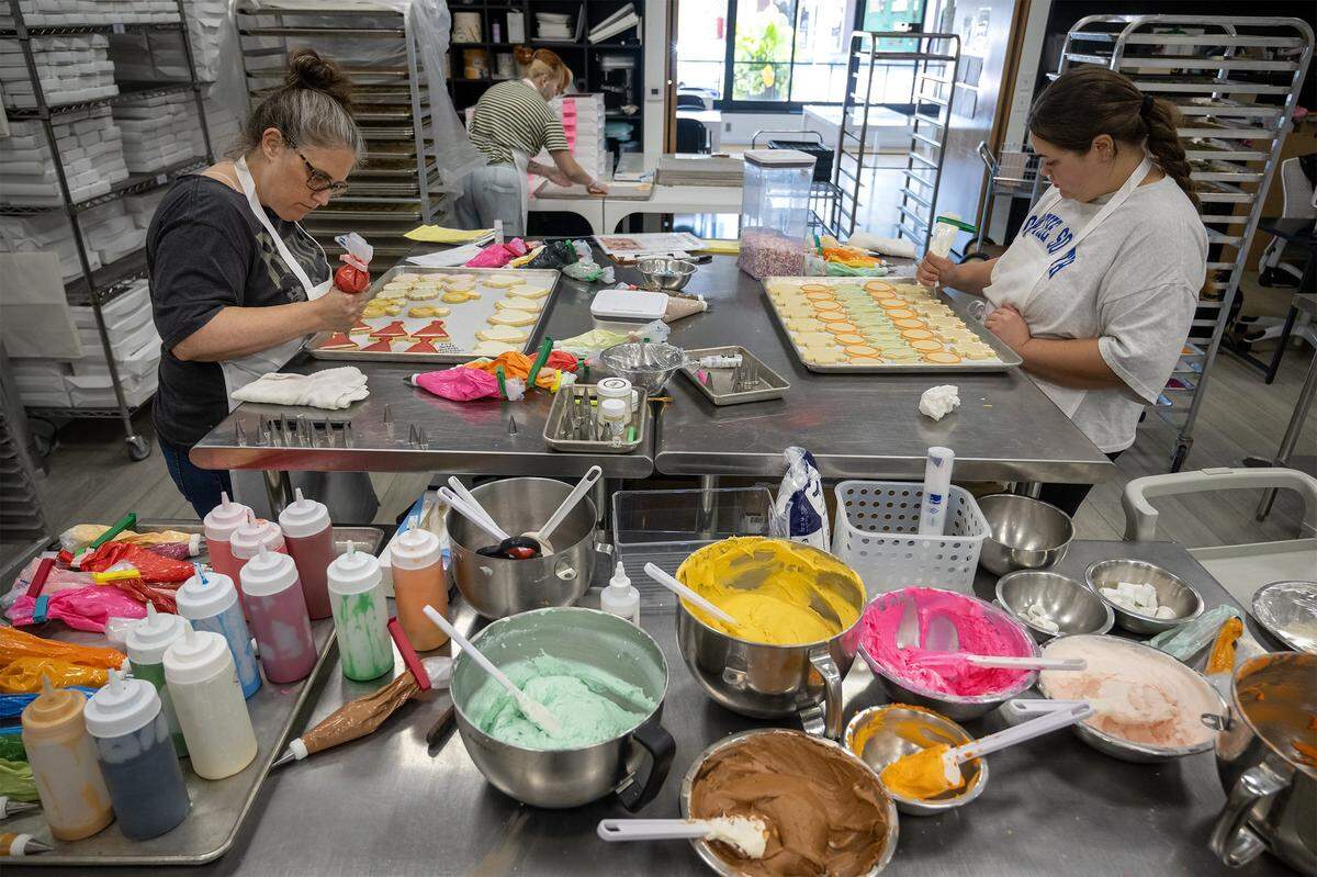 At Dolce Bakery in Prairie Village on Thursday, October 2, 2025, the demand for pop star-themed cookies was clear as Lead cookie decorator Melissa Ritter (left) was busy icing Chappell Roan-themed sugar cookies while cookie decorator Corinna Humiston focused on Taylor Swift designs, reflecting the significant local demand for treats celebrating the two artists.