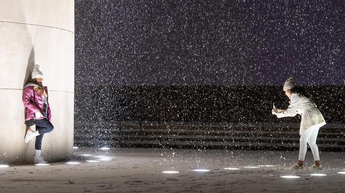 Viviana Torres takes a picture of Karla Hernández-Naranjo as snow falls at the World War I Museum and Memorial on Saturday, Nov. 25, 2023, in Kansas City.