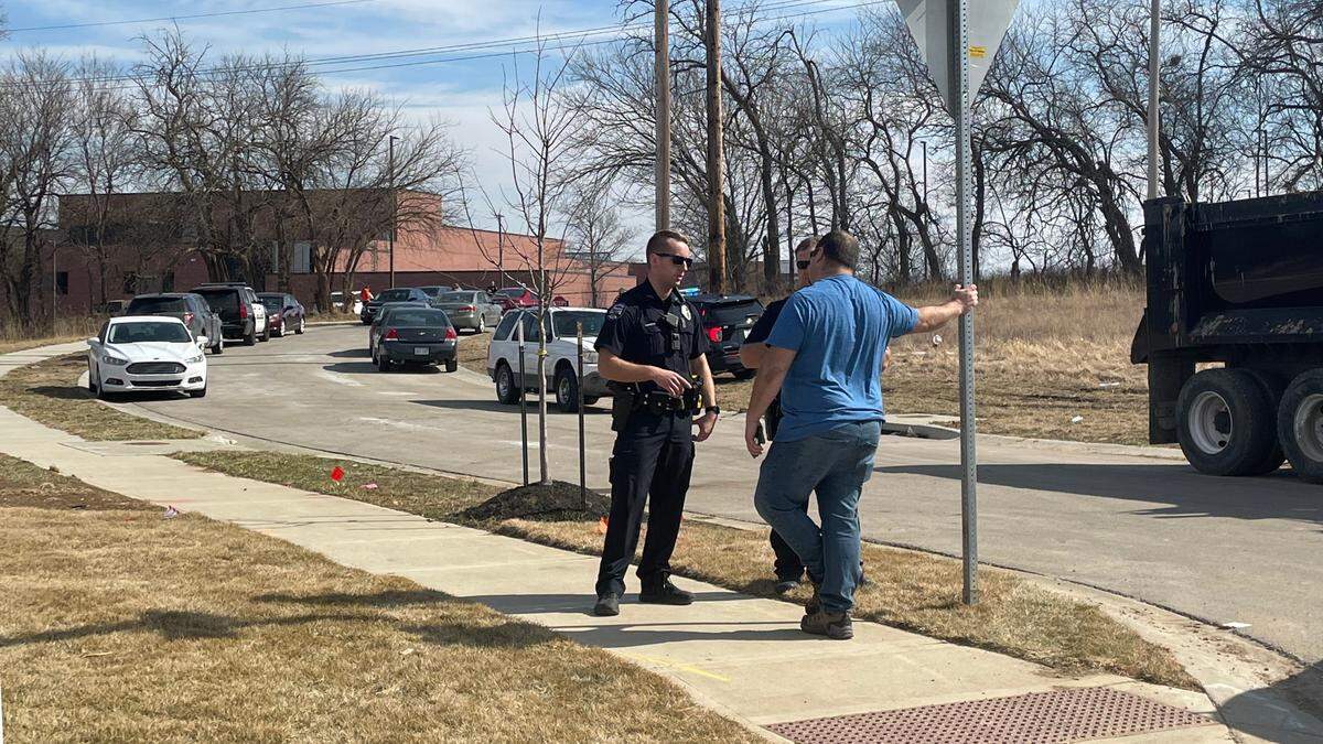 Ryan Forshee, right, who went to check on his daughter who is a freshman at Olathe East High School, meets with a police officer near 127th and South Black Bob in Olathe after reports of a shooting at the school.