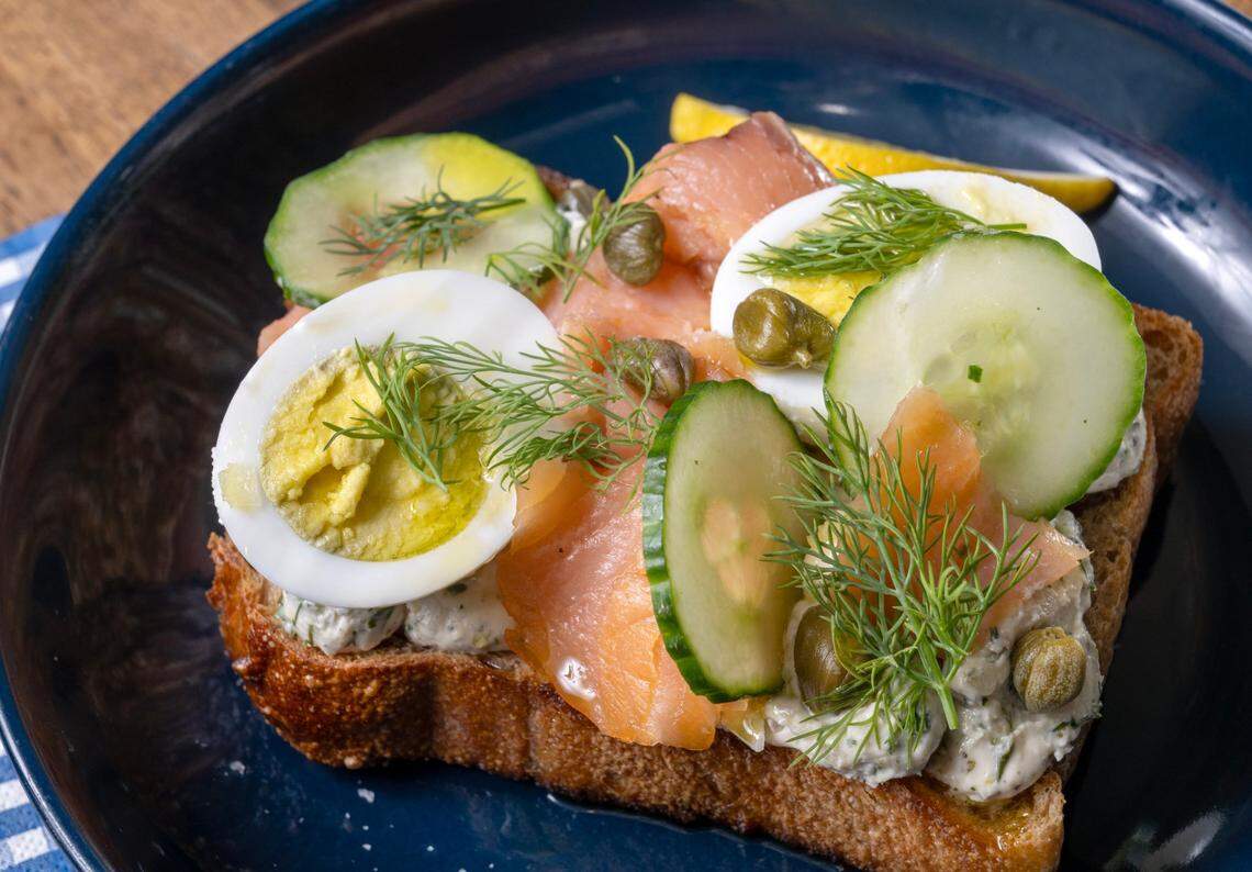 Smoked Salmon toast features Ibis country bread, herby feta, hard-boiled egg, capers, cucumber, lemon, fresh herbs for $11 at Hemma Hemma.