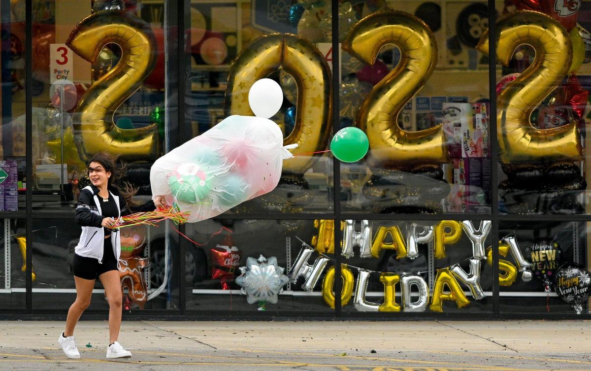 Braced against strong gusts of wind, Cadence Sosa of Merriam, 17, who donned shorts on an unseasonable warm December day, holds on tight to balloons as she runs to her car. Cadence and her sister Brianda Sosa picked up the party decorations from Party City in Merriam Wednesday, Dec. 15, 2021. The National Weather Service issued a high wind warning. Gusts up to 60 mph were expected.