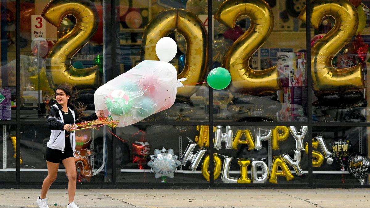 Braced against strong gusts of wind, Cadence Sosa of Merriam, 17, who donned shorts on an unseasonable warm December day, holds on tight to balloons as she runs to her car. Cadence and her sister Brianda Sosa picked up the party decorations from Party City in Merriam Wednesday, Dec. 15, 2021. The National Weather Service issued a high wind warning. Gusts up to 60 mph were expected.