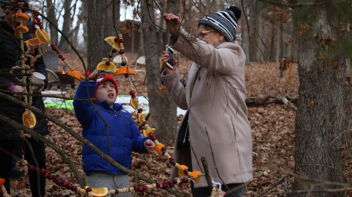 Overland Park resident Bradley Silk, 5, and volunteer Judy Moeller work together to drape edible ornaments on a tree at the Overland Park Arboretum.