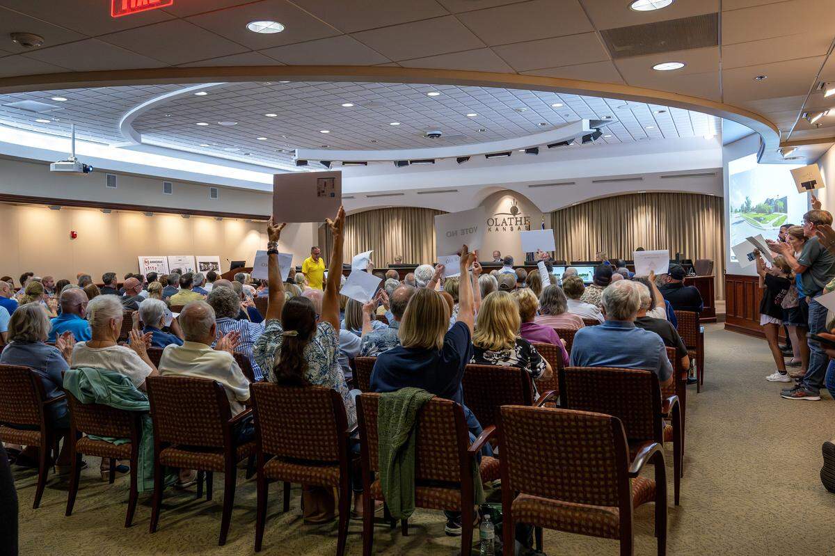Residents hold signs and applaud during the Olathe City Council meeting on Tuesday, Sept. 16, 2025, at Olathe City Hall. The council considered a proposed Lineage Cold Storage facility near 175th Street and Lone Elm Road.