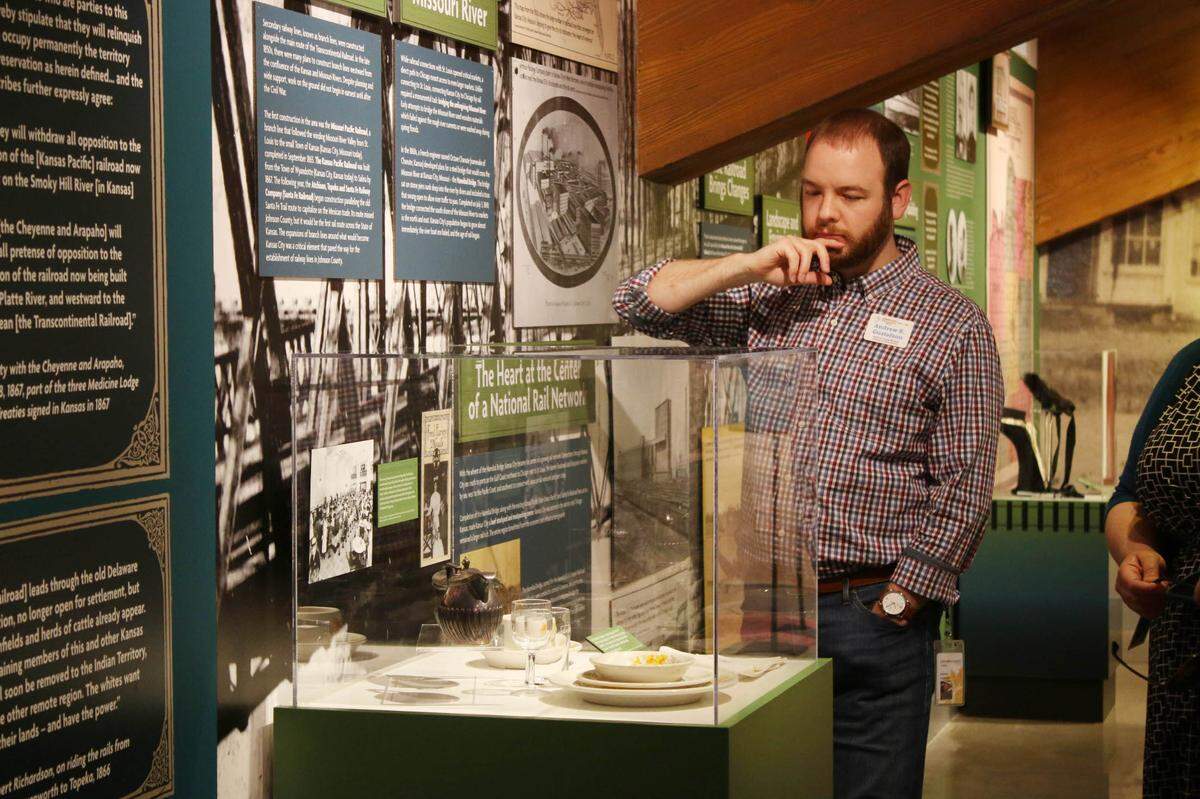Andrew Gustafson, curator of interpretation at the Johnson County Museum, looks at a display of dishes in the museum’s new train exhibit.