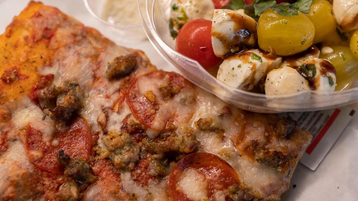 On the menu at the new Khalia’s Pizzeria in the Parlor food hall in the Crossroads: a slice of sausage and pepperoni pizza with a side of Parmesan cheese and a caprese salad.