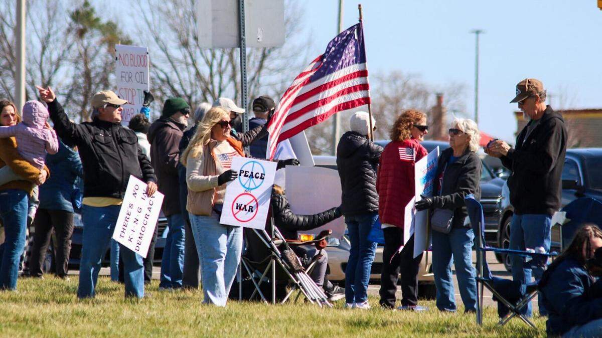 Protesters hold signs in opposition to the war in Iran at College Boulevard and Metcalf Avenue for the No Kings rally March 28, 2026.