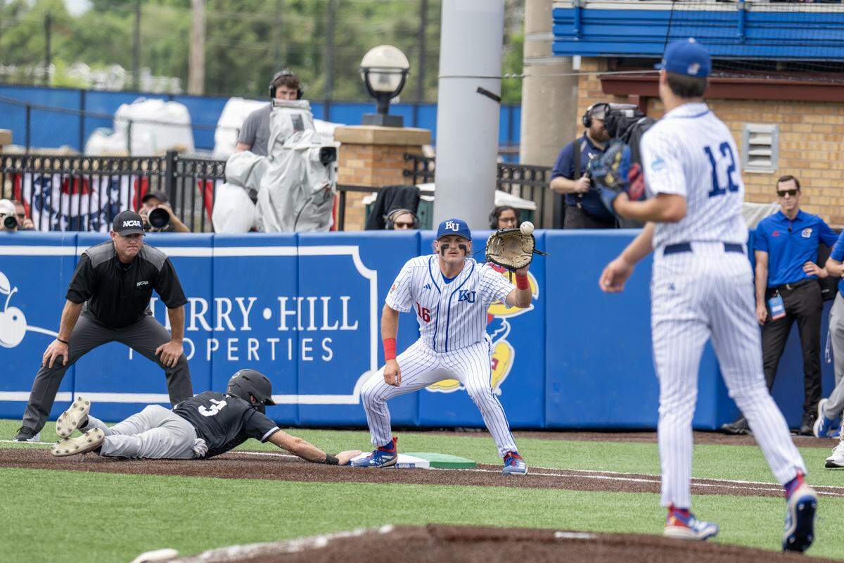 Kansas Jayhawks pitcher Dominic Voegele (12) throws to first base in an attempt to get out Northeastern Huskies outfielder Ryan Gerety (3) in the first inning during an NCAA baseball tournament game at Hoglund Ballpark on Friday, May 29, 2026, in Lawrence.