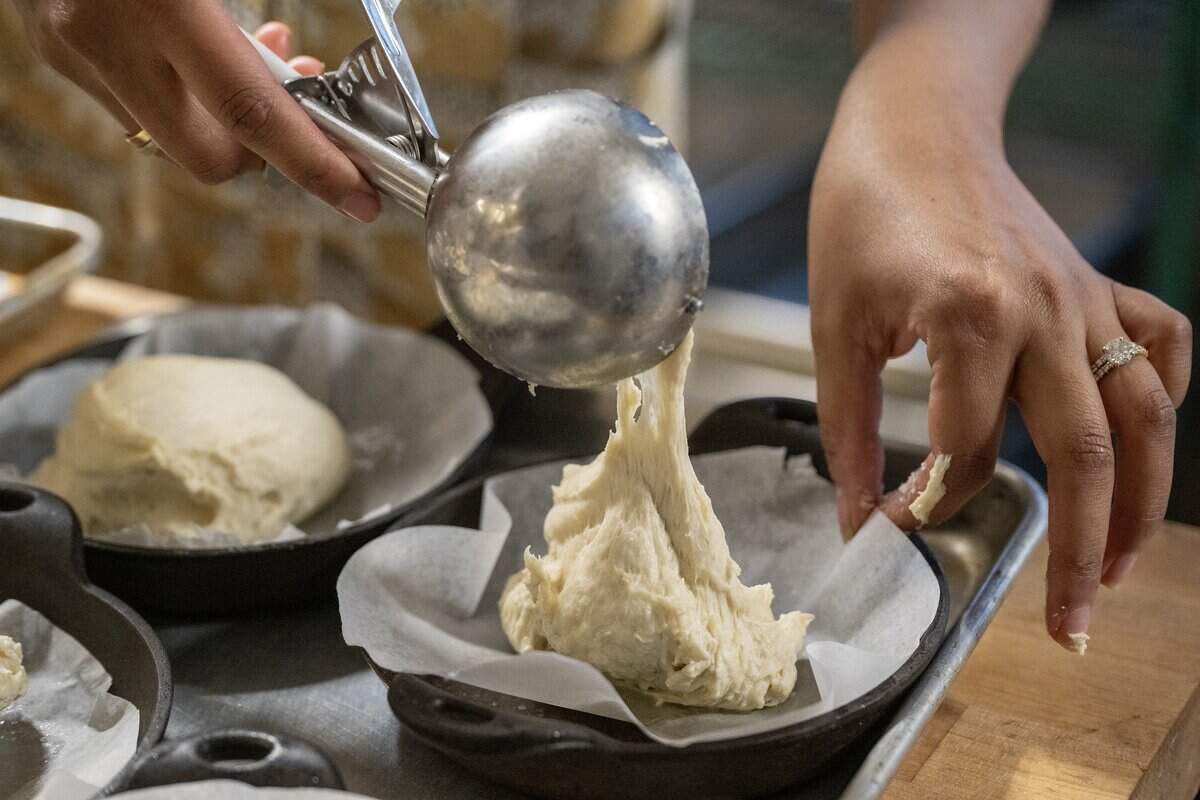 Chef/owner Swetha Newcomb adds scoops of focaccia dough to a pan as she was creating a new bread dish in the kitchen on Wednesday, Feb. 25, 2026, at Of Course Kitchen & Co., 7753 W 159th St., in Overland Park. 