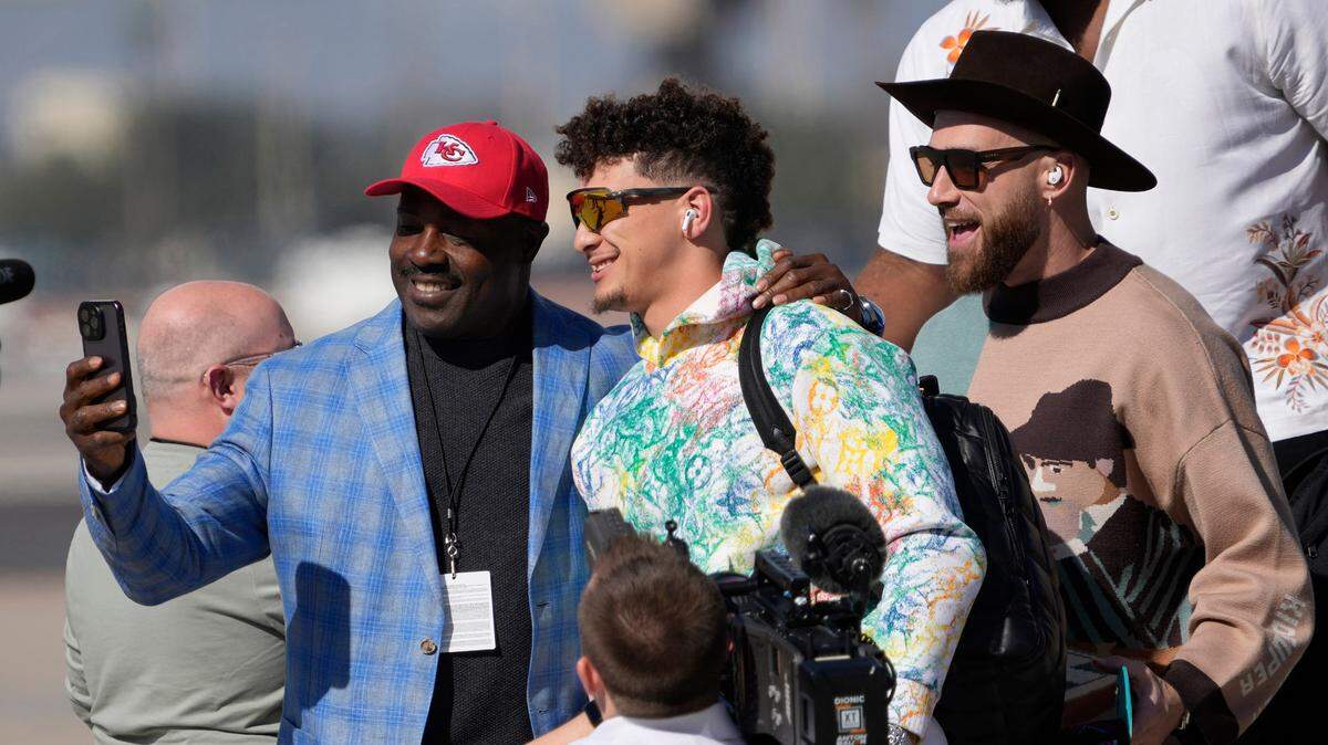 Former Kansas City Chiefs running back Christian Okoye (left) grabs a selfie with Chiefs QB Patrick Mahomes (center) and tight end Travis Kelce (right) after arriving at Goldwater Air National Guard Base on Feb. 5, 2023.