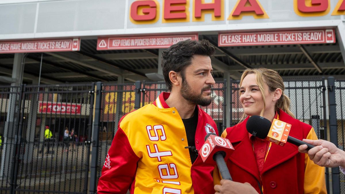 Tyler Hynes, left, and co-star Hunter King talk to the media during a break in filming “Holiday Touchdown: A Chiefs Love Story” at GEHA Field at Arrowhead Stadium Tuesday.