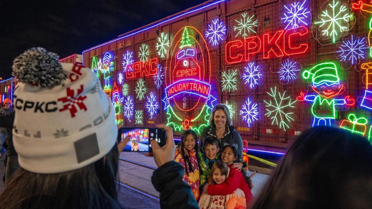 Mary Beth Leistad poses for a photo with her children and neighbors next to a festively decorated train car during the Canadian Pacific Kansas City Holiday Train event at Union Station on Monday, Nov. 27, 2023, in Kansas City. In its 25th annual journey, the CPKC Holiday Train brought fourteen decorated rail cars, serving a charitable purpose by supporting food banks, obtaining contributions and raising awareness about food insecurity issues.