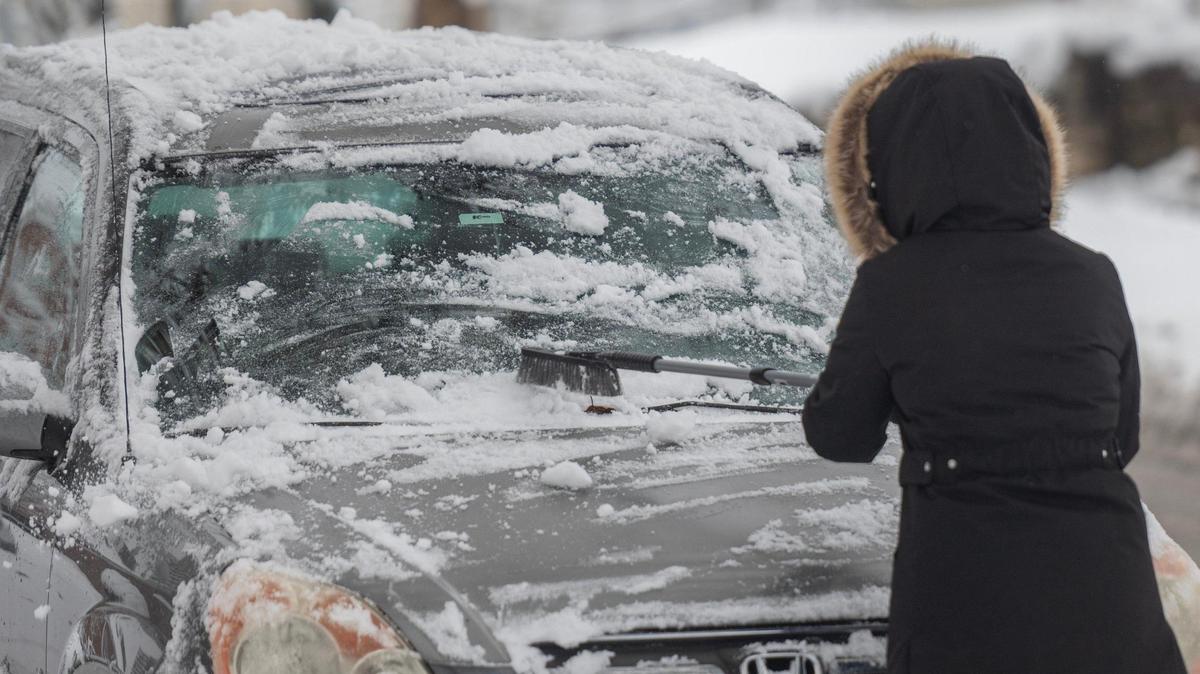A commuter brushes snow off their car window on Tuesday, Jan. 9, 2024, in Kansas City.