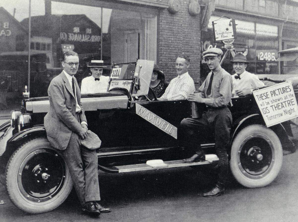 Walt Disney (in back seat with camera tripod) and Laugh-O-gram employees film a Troost Avenue neighborhood parade, probably in 1922. The sign on the car reads, “These pictures will be shown at the Isis Theatre tomorrow night.”