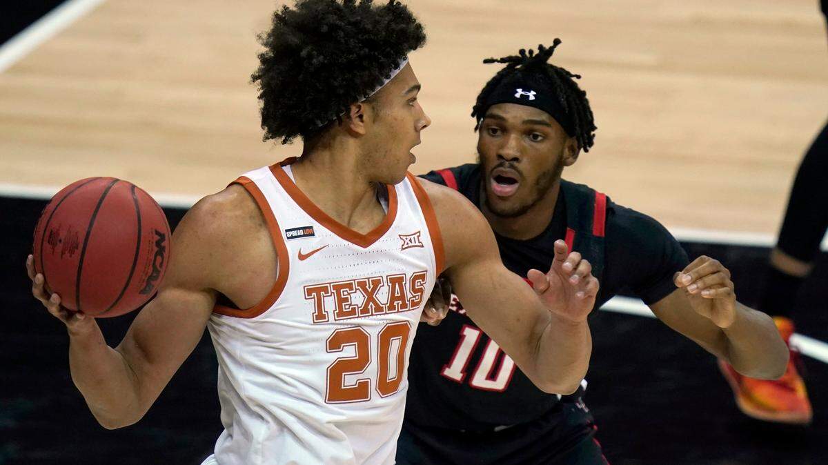 Texas forward Jericho Sims (20) looks to pass while covered by Texas Tech Red forward Tyreek Smith (10) during the first half of an NCAA college basketball game in the quarterfinal round of the Big 12 men’s tournament in Kansas City, Mo., Thursday, March 11, 2021. (AP Photo/Orlin Wagner)