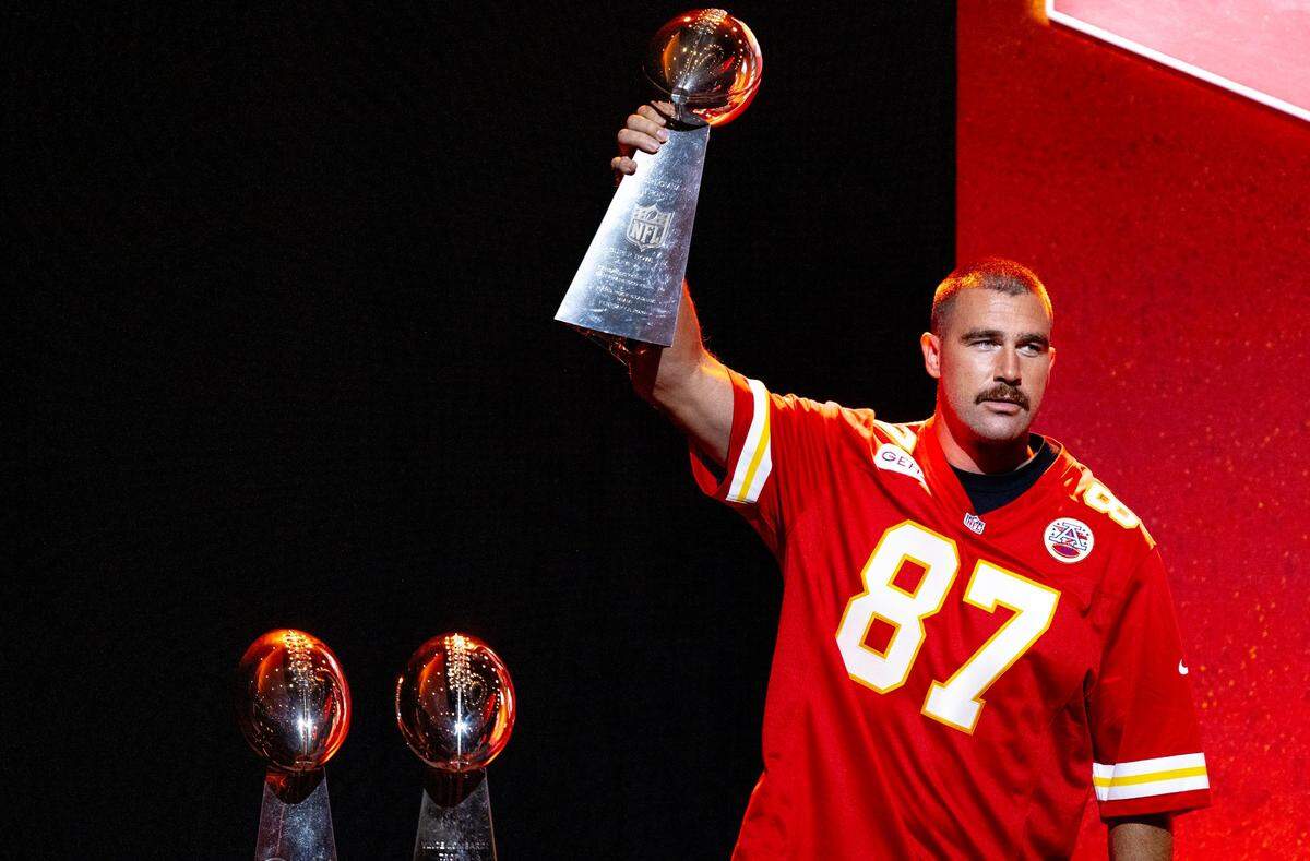 Kansas City Chiefs tight end Travis Kelce hoists one of three Lombardi Trophies during the Chiefs Kickoff Luncheon at the Loews Hotel on Thursday, Aug. 24, 2023, in Kansas City.