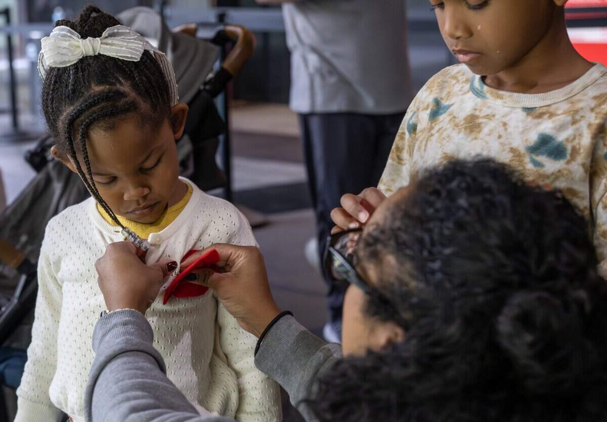 Christa Moss pins a felt poppy on her 4-year-old daughter Emma Moss in honor of Veterans Day at the National WWI Museum and Memorial on Tuesday, Nov. 11, 2025, in Kansas City.