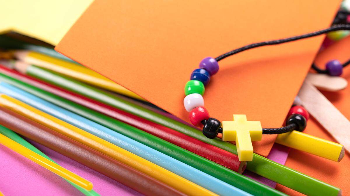 Color pencils, plastic cross necklace and stars on yellow background with copy space. School, craft,Church, Selected focus. separation of church and state