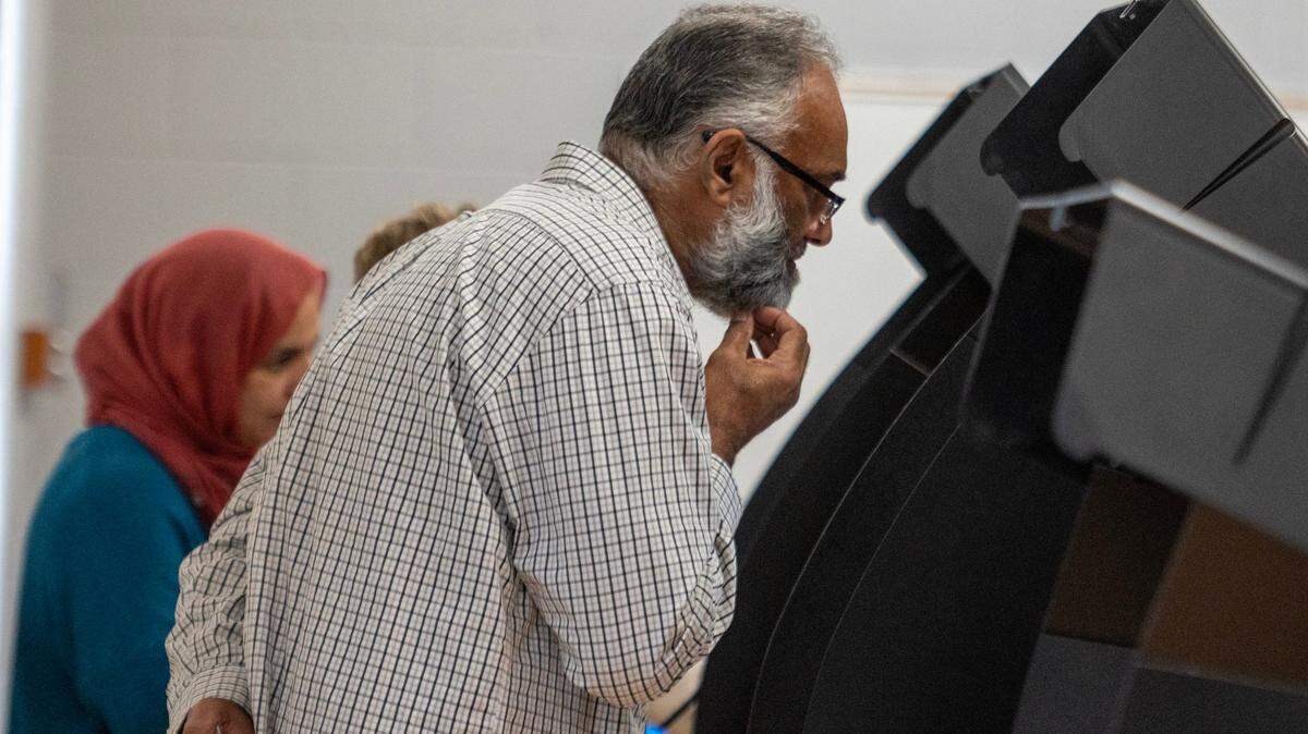 Mubashir Qureshi scratches his beard as he casts his ballot at Blue Valley Recreation Center in Overland Park on Tuesday, Nov. 7, 2023.